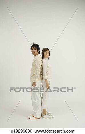 Stock Image - Young couple standing back to back. Fotosearch
