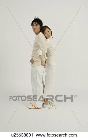 Young couple standing back to back View Large Photo Image Stock Image - Young couple standing back to back. Fotosearch