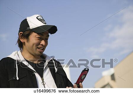 Young man using mobile phone View Large Photo Image Stock Photograph - Young man using mobile phone. Fotosearch