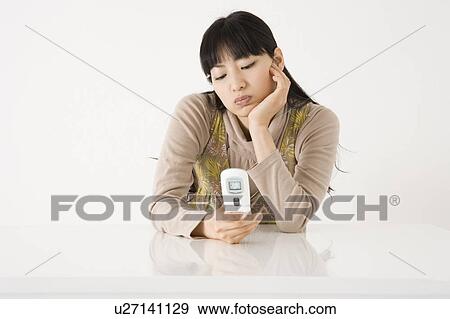 Stock Photo - Angry young woman looking at mobile phone. Fotosearch