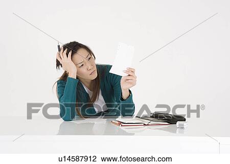 Stock Image - Young woman checking accounts. Fotosearch