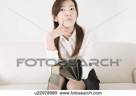 Stock Photo - Young woman holding empty wallet. Fotosearch