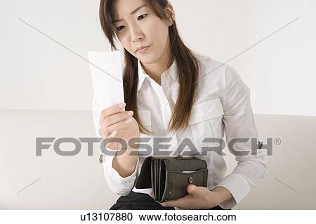 Young woman looking at bill View Large Photo Image Stock Image - Young woman looking at bill. Fotosearch