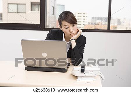 Stock Image - Young woman looking at telephone. Fotosearch