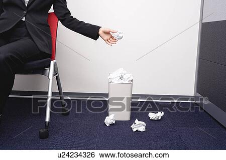 Stock Photograph - Young woman putting ball of paper into wastebasket. Fotosearch