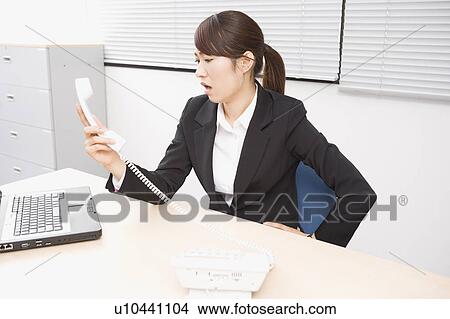 Picture - Young woman shouting at telephone. Fotosearch