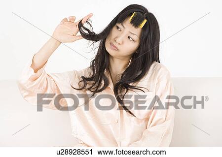 Stock Image - Young woman touching hair. Fotosearch