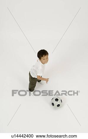Stock Image - Elementary age boy playing with soccer ball. Fotosearch