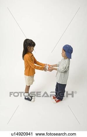 Stock Image - Elementary age child giving gift to friend. Fotosearch