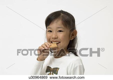 Elementary age girl eating cookie View Large Photo Image Stock Photo - Elementary age girl eating cookie. Fotosearch