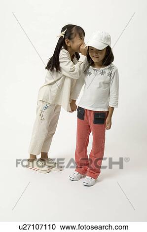 Elementary age girl whispering into friend's ear View Large Photo Image Stock Image - Elementary age girl whispering into friend's ear. Fotosearch