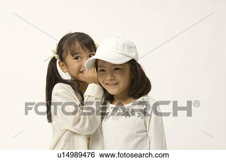 Elementary age girl whispering into friend's ear View Large Photo Image Stock Photograph - Elementary age girl whispering into friend's ear. Fotosearch