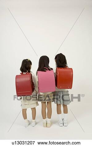 Stock Photo - Three elementary age girls standing, rear view. Fotosearch