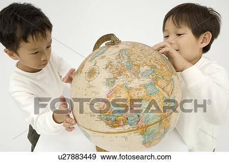 Stock Photo - Two elementary age boys looking at globe. Fotosearch