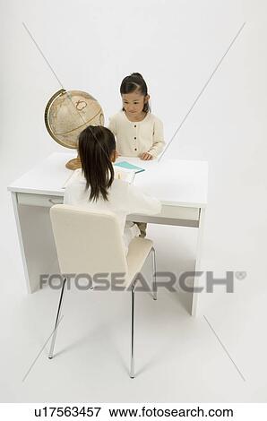 Stock Photo - Two elementary age girls sitting at desk. Fotosearch