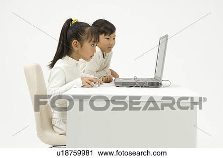 Stock Image - Two elementary age girls using laptop. Fotosearch