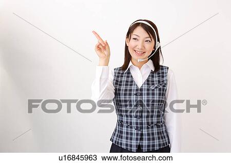 Stock Image - A woman with headset pointing a direction. Fotosearch