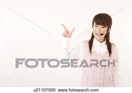 Stock Image - A woman with headset pointing a direction. Fotosearch