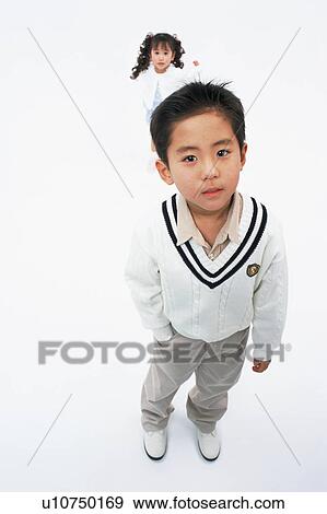 Stock Photo - A boy looking at camera while a girl stands behind. Fotosearch