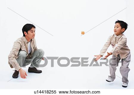Stock Photography - A boy trying to catch a small cube while father watches. Fotosearch