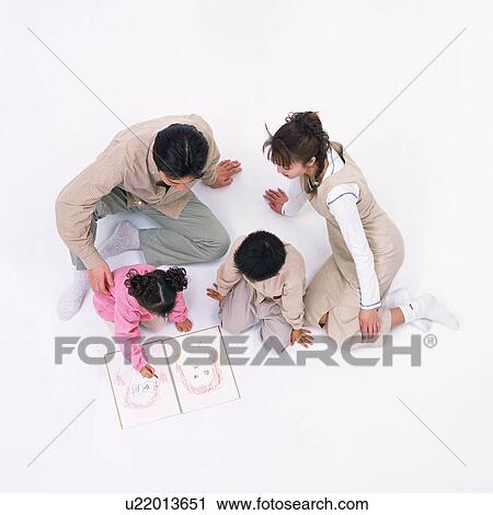 Stock Image - A girl scribbling out a human face and parents looking on. Fotosearch