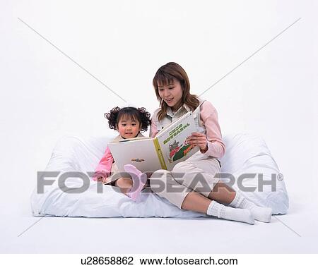 Stock Image - A mother reading a book to her daughter. Fotosearch
