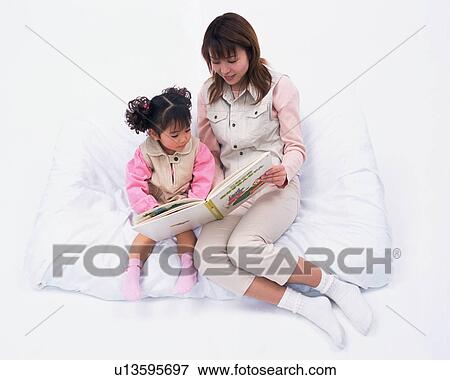 A mother reading a book to her daughter View Large Photo Image Stock Photo - A mother reading a book to her daughter. Fotosearch