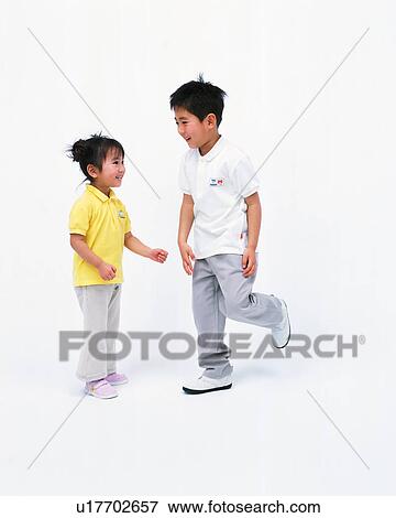 Stock Photo - A small girl looking at her brother lifting his leg up. Fotosearch