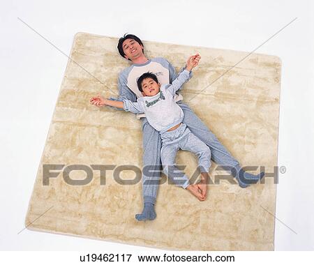 High angle view of a boy and his father lying on floor View Large Photo Image Stock Photo - High angle view of a boy and his father lying on floor. Fotosearch