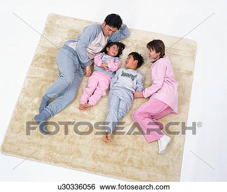 Stock Photograph - High angle view of a happy family lying on floor. Fotosearch