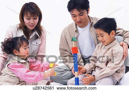 Stock Image - Parents looking on as their children play with toys. Fotosearch
