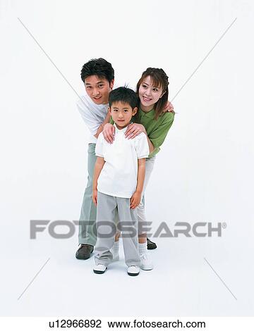 Stock Image - A boy looking at camera with his parents standing behind him. Fotosearch