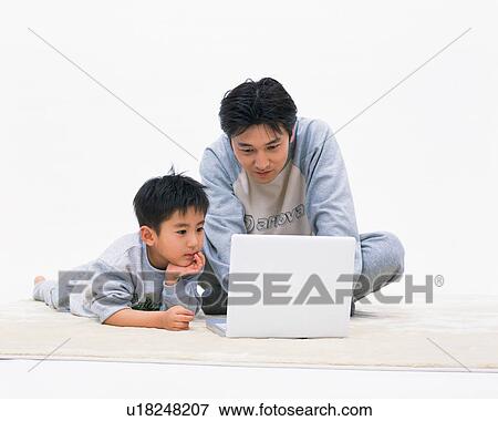 Stock Photo - A man working on computer while his son looks on. Fotosearch