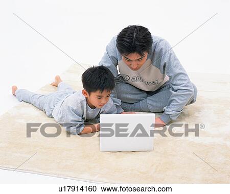 Stock Image - A small boy along with his father looking at laptop. Fotosearch