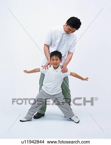 Picture - A small boy sprawling with his father standing behind him. Fotosearch