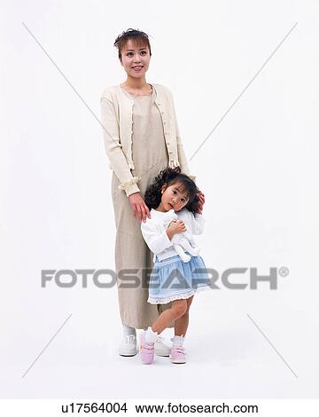 Picture - A small girl holding her toy with her mother standing next to her. Fotosearch