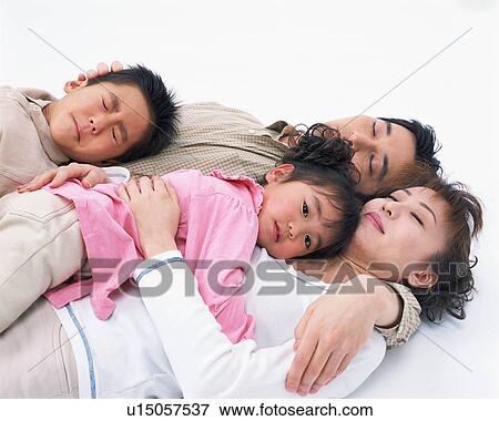 Stock Photo - A small girl looking at camera while parents sleeping. Fotosearch