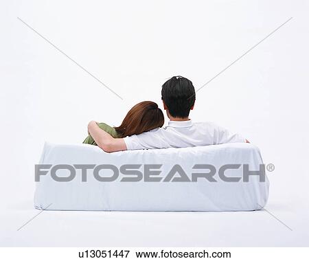 Stock Photo - Rear view of a couple resting on couch. Fotosearch