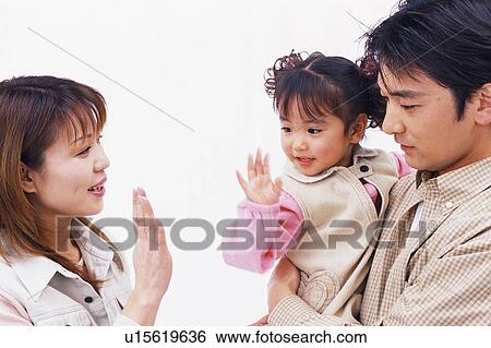 Side view of a small girl giving high-five to her mother View Large Photo Image Stock Photograph - Side view of a small girl giving high-five to her mother. Fotosearch