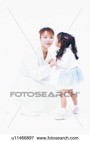 Stock Photo - Side view of a small girl kissing her mother. Fotosearch
