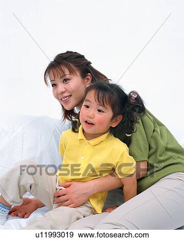 Stock Photo - Side view of a woman holding her daughter. Fotosearch