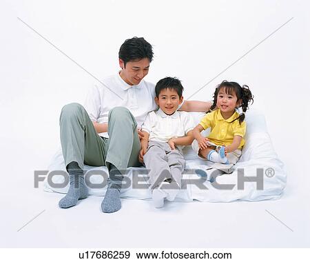 Stock Photo - Two children along with their father resting on couch. Fotosearch