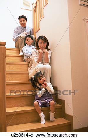 Stock Photography - A family looking at camera as they sit on stairs. Fotosearch