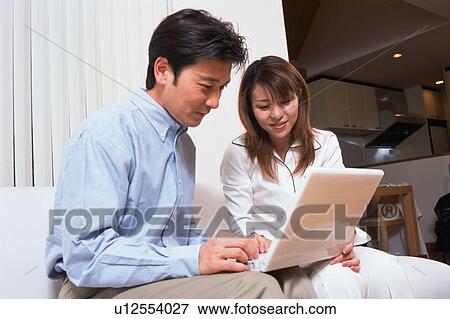 Stock Photo - A man along with his wife looking at laptop. Fotosearch