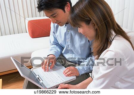 A man along with his wife looking at laptop View Large Photo Image Stock Photo - A man along with his wife looking at laptop. Fotosearch