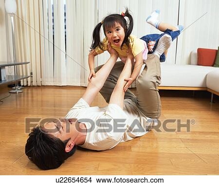 Picture - A man heaving his daughter with his legs. Fotosearch