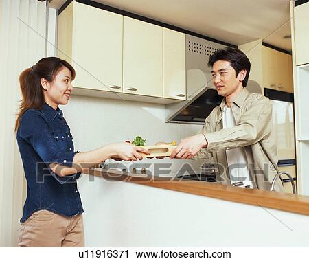 Stock Image - A man helping his wife to serve meal. Fotosearch