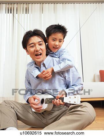 Stock Photography - A man playing the guitar with his son. Fotosearch