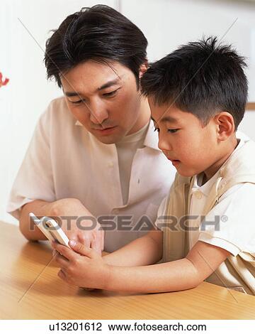 A small boy along with his father looking at mobile phone View Large Photo Image Stock Image - A small boy along with his father looking at mobile phone. Fotosearch