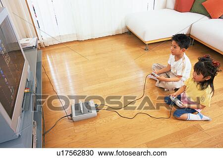 A small boy playing video game along with his sister View Large Photo Image Stock Image - A small boy playing video game along with his sister. Fotosearch